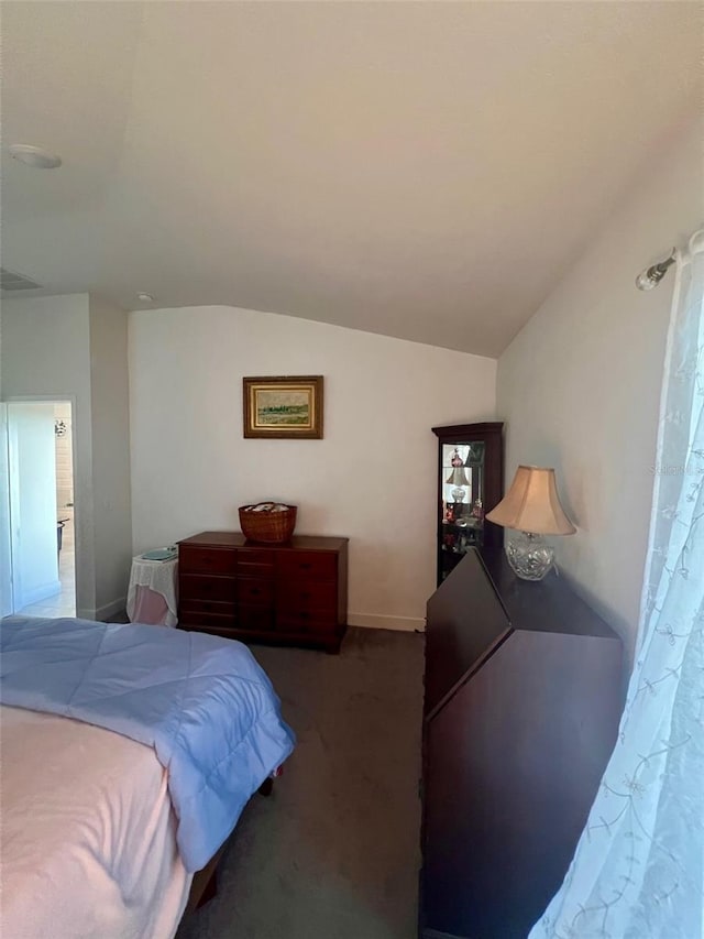 bedroom featuring lofted ceiling, visible vents, and dark carpet