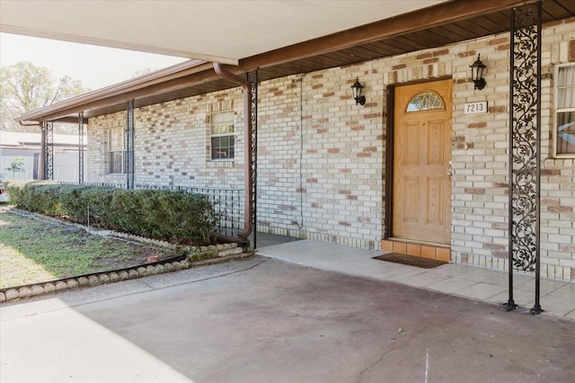 entrance to property featuring covered porch and brick siding