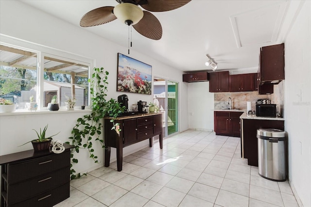 kitchen with light tile patterned floors, ceiling fan, light countertops, black microwave, and backsplash