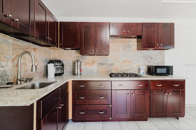 kitchen featuring decorative backsplash, dark brown cabinets, black microwave, a sink, and gas cooktop