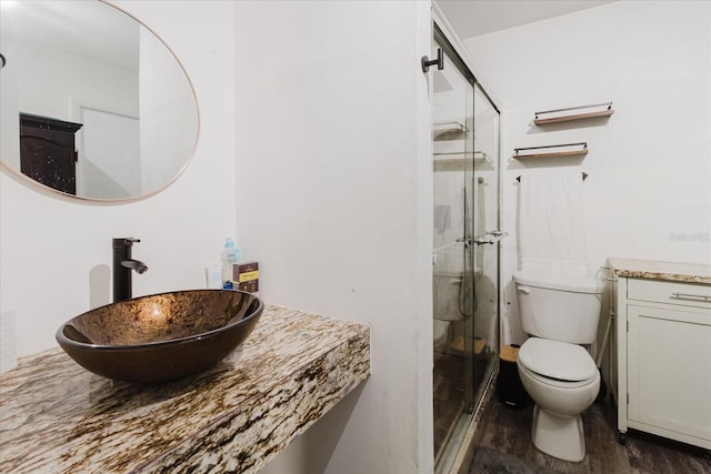 bathroom featuring toilet, a shower stall, wood finished floors, and vanity