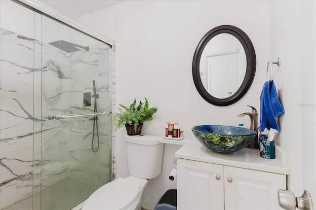 bathroom with toilet, a marble finish shower, and vanity