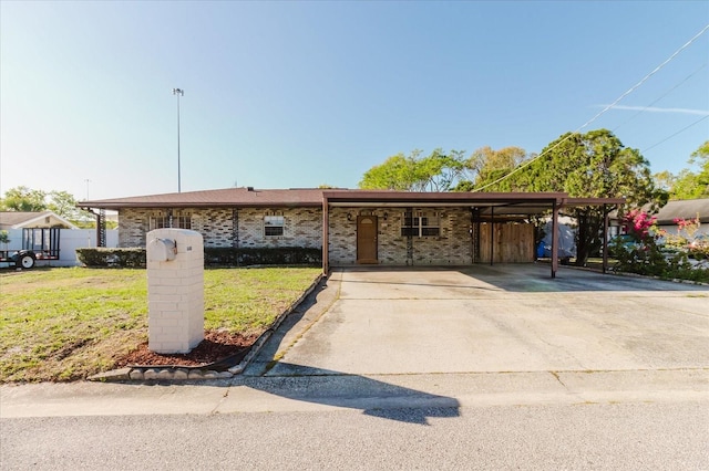 view of front of house featuring concrete driveway, a carport, brick siding, and a front yard