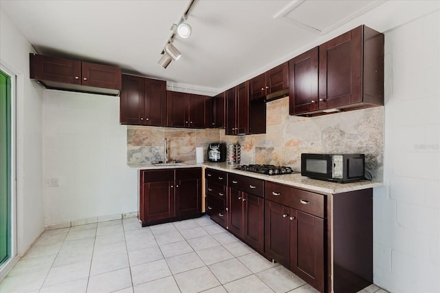 kitchen featuring black microwave, tasteful backsplash, a sink, and gas stovetop