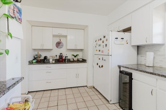 kitchen featuring light tile patterned flooring, beverage cooler, white cabinetry, freestanding refrigerator, and decorative backsplash