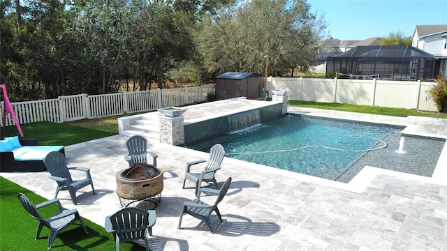 view of swimming pool featuring an outdoor fire pit, a fenced backyard, a patio, and an outbuilding