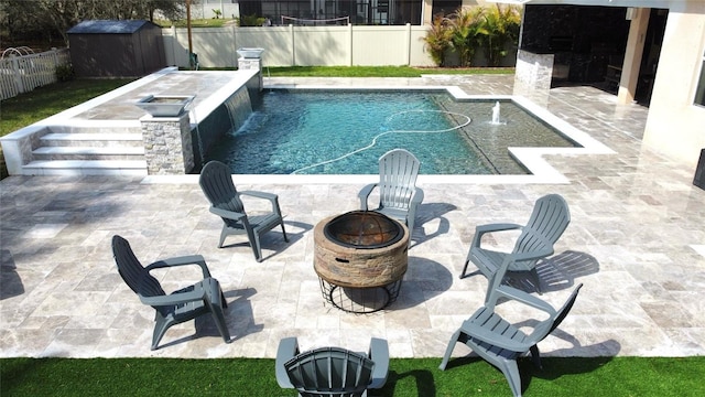 view of swimming pool with a fire pit, a patio area, a fenced backyard, and an outbuilding