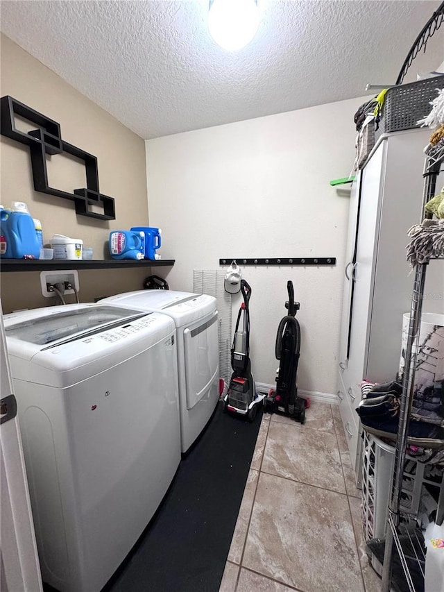 washroom featuring washer and dryer, laundry area, a textured ceiling, and baseboards