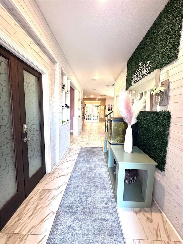 mudroom with marble finish floor, a textured ceiling, and french doors