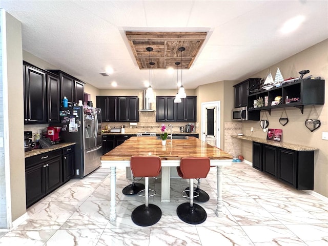 kitchen featuring marble finish floor, appliances with stainless steel finishes, decorative backsplash, and dark cabinets