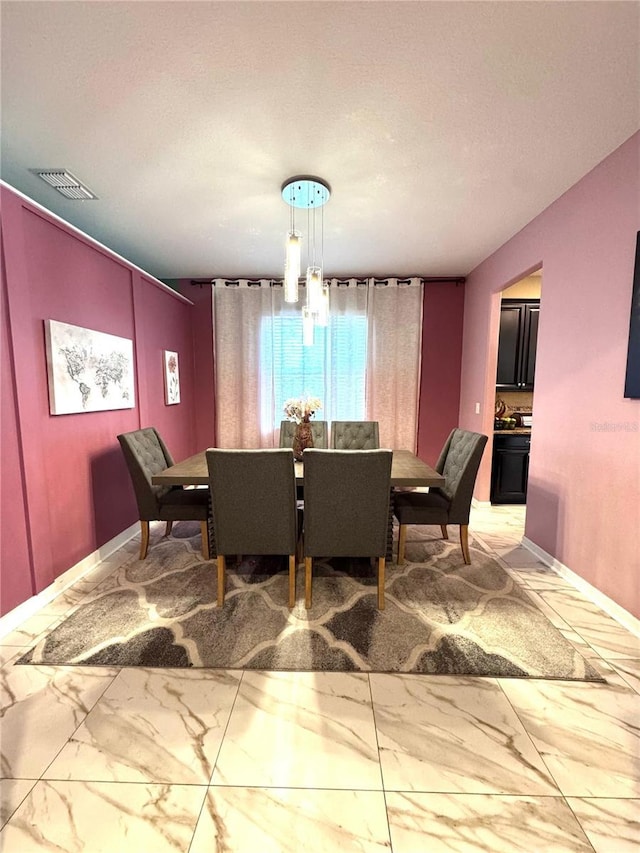 dining space with a textured ceiling, marble finish floor, visible vents, and baseboards