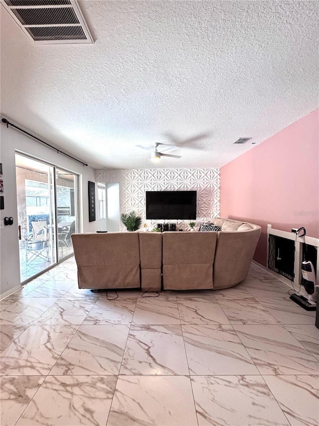 living area with a textured ceiling, marble finish floor, and visible vents