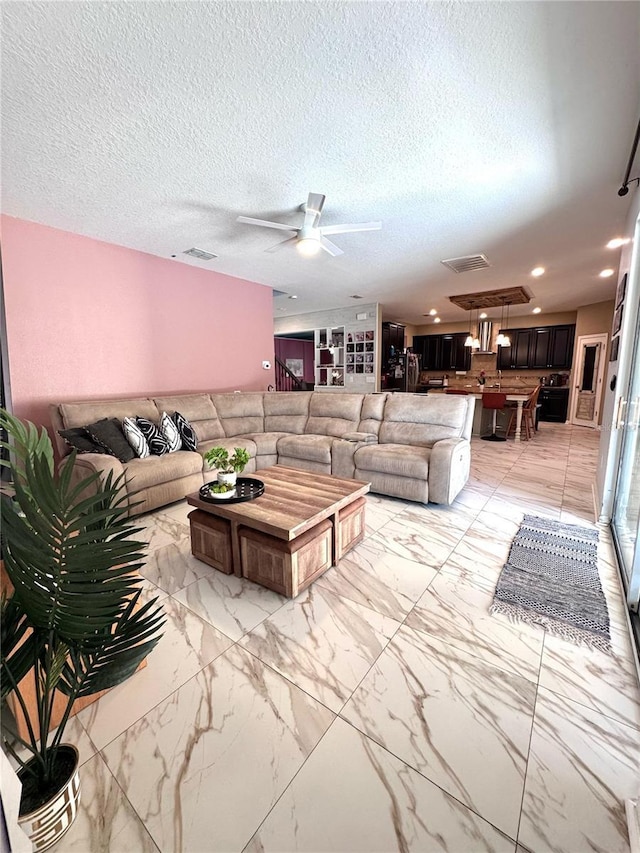 living room featuring a textured ceiling, visible vents, a ceiling fan, and recessed lighting