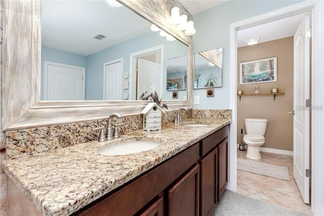 full bathroom with toilet, double vanity, a sink, and visible vents