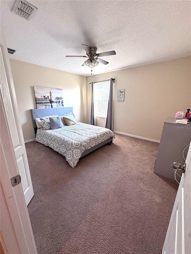 carpeted bedroom with ceiling fan, a textured ceiling, visible vents, and baseboards