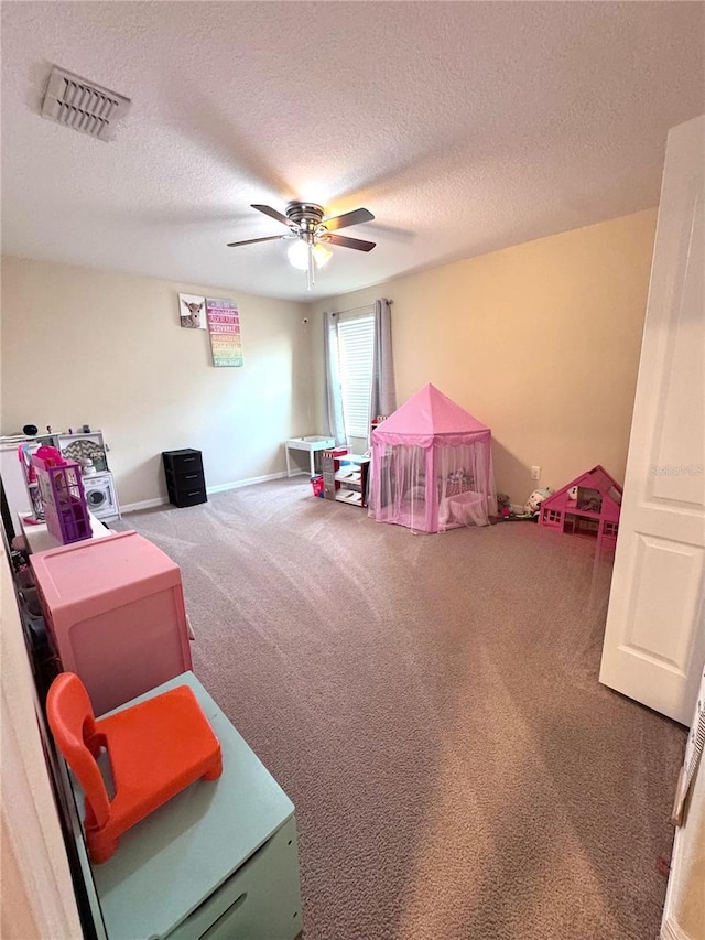 game room featuring ceiling fan, a textured ceiling, carpet flooring, and visible vents