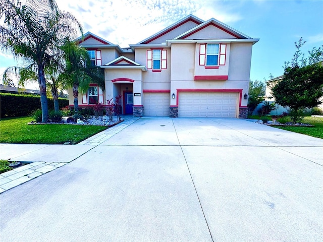 view of front of house featuring a garage, driveway, stone siding, stucco siding, and a front yard