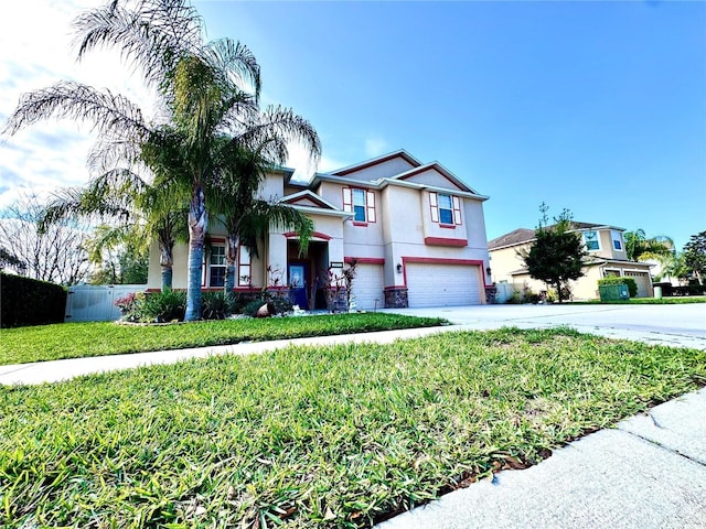 view of front facade with an attached garage, fence, concrete driveway, stucco siding, and a front lawn