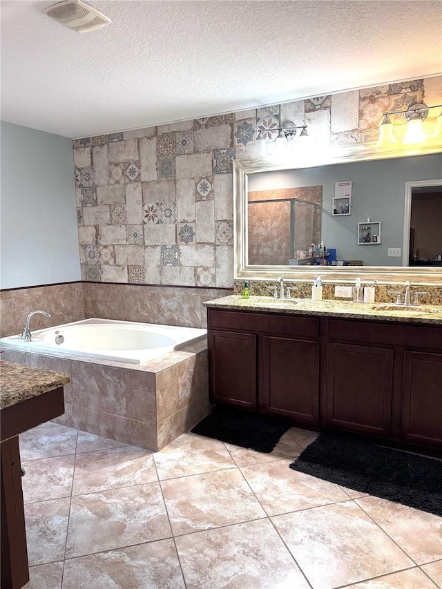 bathroom featuring a garden tub, a textured ceiling, visible vents, and a sink