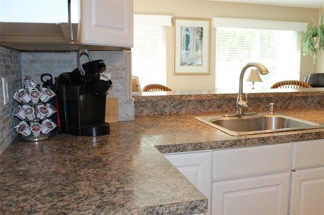 kitchen featuring dark countertops, a sink, white cabinetry, and a healthy amount of sunlight