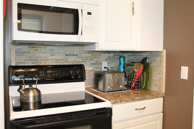 kitchen with white microwave, stone countertops, black range with electric stovetop, white cabinetry, and backsplash