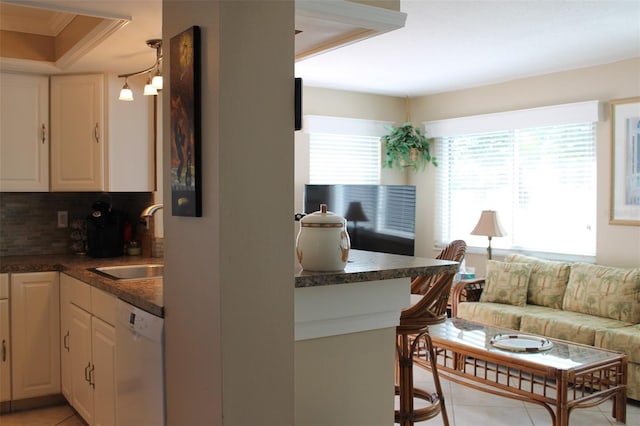 kitchen featuring dark countertops, dishwasher, a sink, and light tile patterned floors