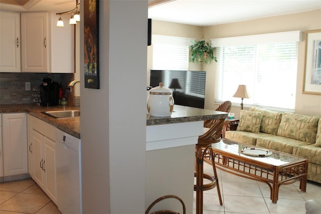 kitchen featuring dark countertops, white dishwasher, white cabinetry, and a sink