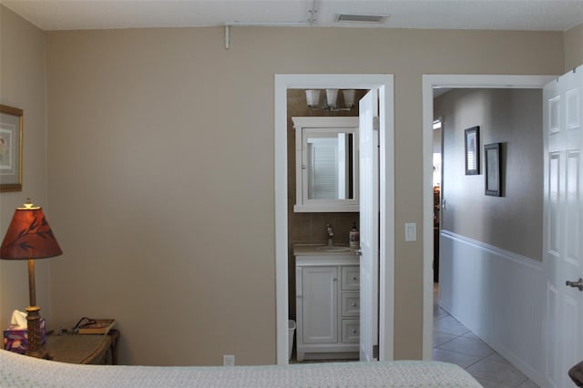 bedroom featuring light tile patterned floors, a sink, and visible vents