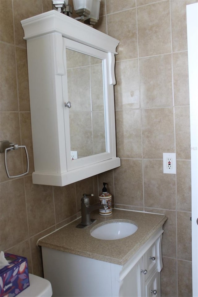 half bath with toilet, tile walls, and vanity