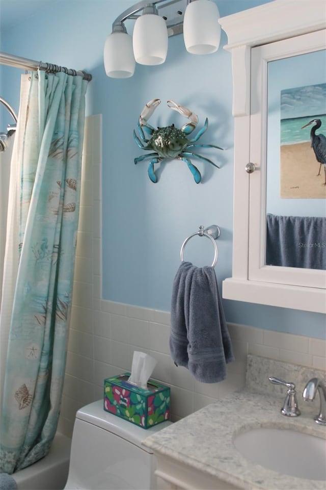 full bathroom featuring toilet, tile walls, shower / tub combo with curtain, and vanity