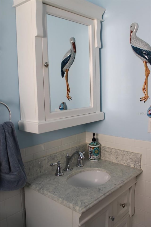 bathroom featuring a wainscoted wall, vanity, and tile walls