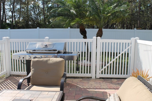 view of patio featuring a grill and fence