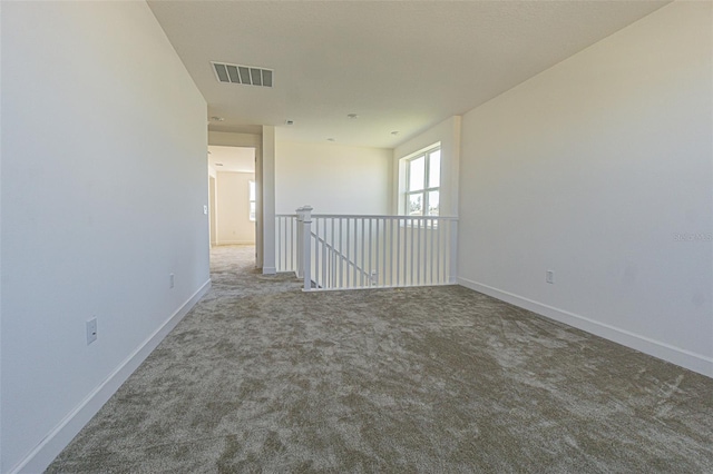 spare room with carpet, visible vents, and baseboards