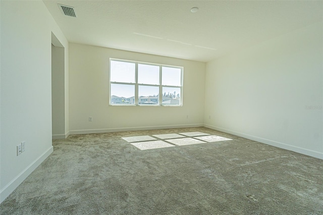 empty room featuring light carpet, visible vents, and baseboards