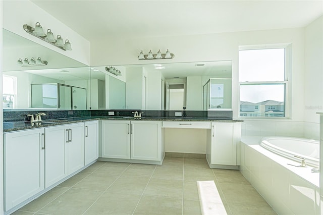 bathroom with double vanity, a stall shower, tile patterned floors, a garden tub, and a sink