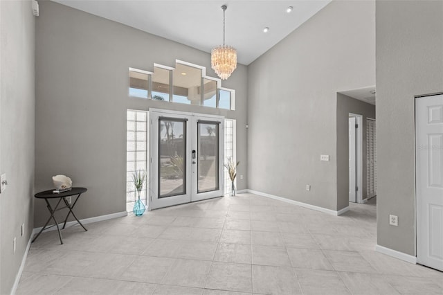 entryway featuring light tile patterned floors, baseboards, a towering ceiling, french doors, and a notable chandelier