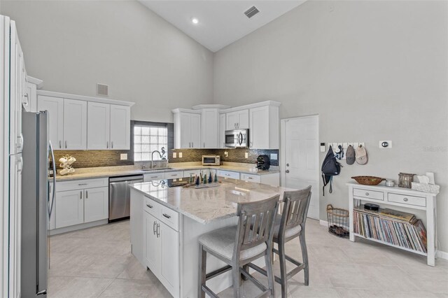 kitchen featuring visible vents, stainless steel appliances, a sink, and a center island