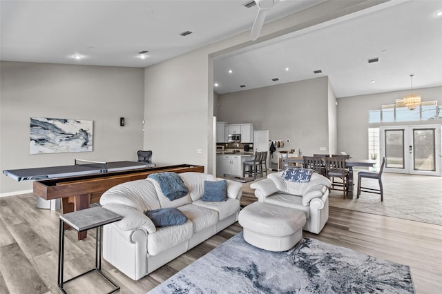 living area featuring light wood finished floors, a high ceiling, baseboards, and recessed lighting