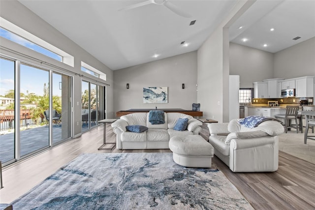 living room with light wood-style floors, high vaulted ceiling, a ceiling fan, and recessed lighting