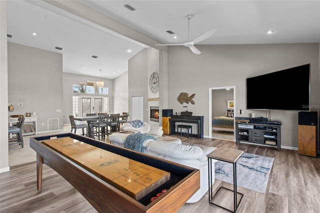 living area featuring visible vents, a ceiling fan, wood finished floors, beamed ceiling, and high vaulted ceiling