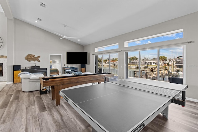 game room with wood finished floors, plenty of natural light, a glass covered fireplace, and visible vents