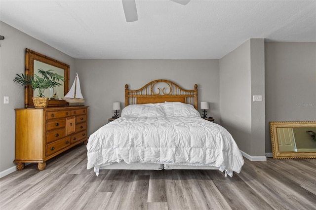 bedroom with a ceiling fan, baseboards, and wood finished floors