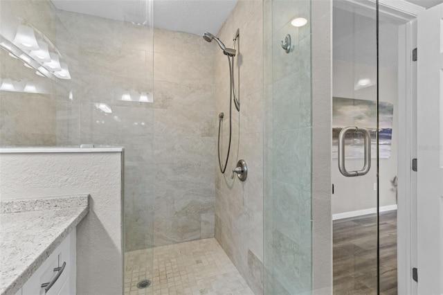 bathroom with tiled shower and vanity