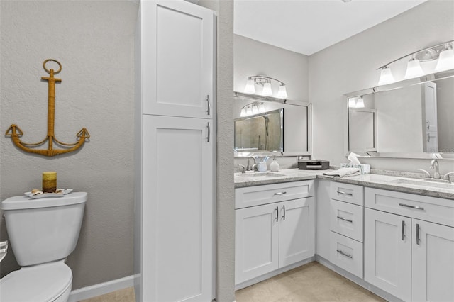 full bath featuring a textured wall, double vanity, a sink, and toilet