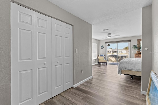 bedroom featuring visible vents, a textured wall, wood finished floors, access to outside, and baseboards