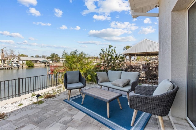 view of patio featuring a water view, fence, and an outdoor hangout area