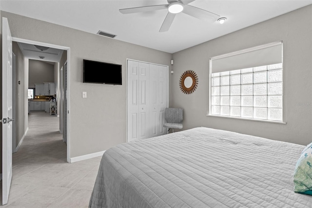 bedroom featuring light tile patterned floors, a closet, visible vents, ceiling fan, and baseboards