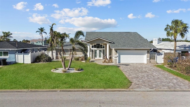 view of front of property featuring decorative driveway, a gate, fence, a garage, and a front lawn