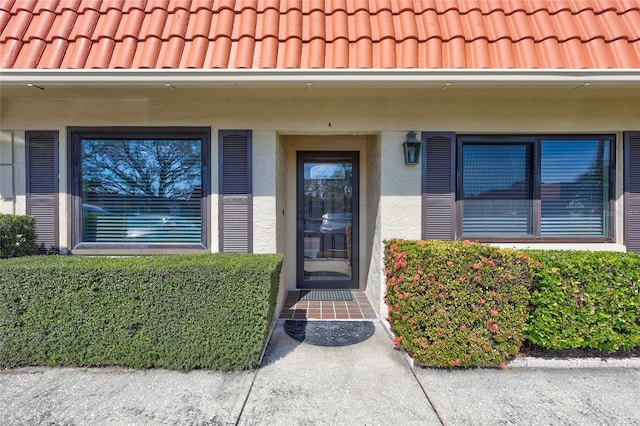 entrance to property featuring a tile roof and stucco siding