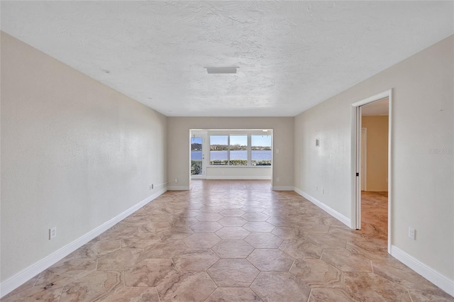 empty room featuring a textured ceiling and baseboards